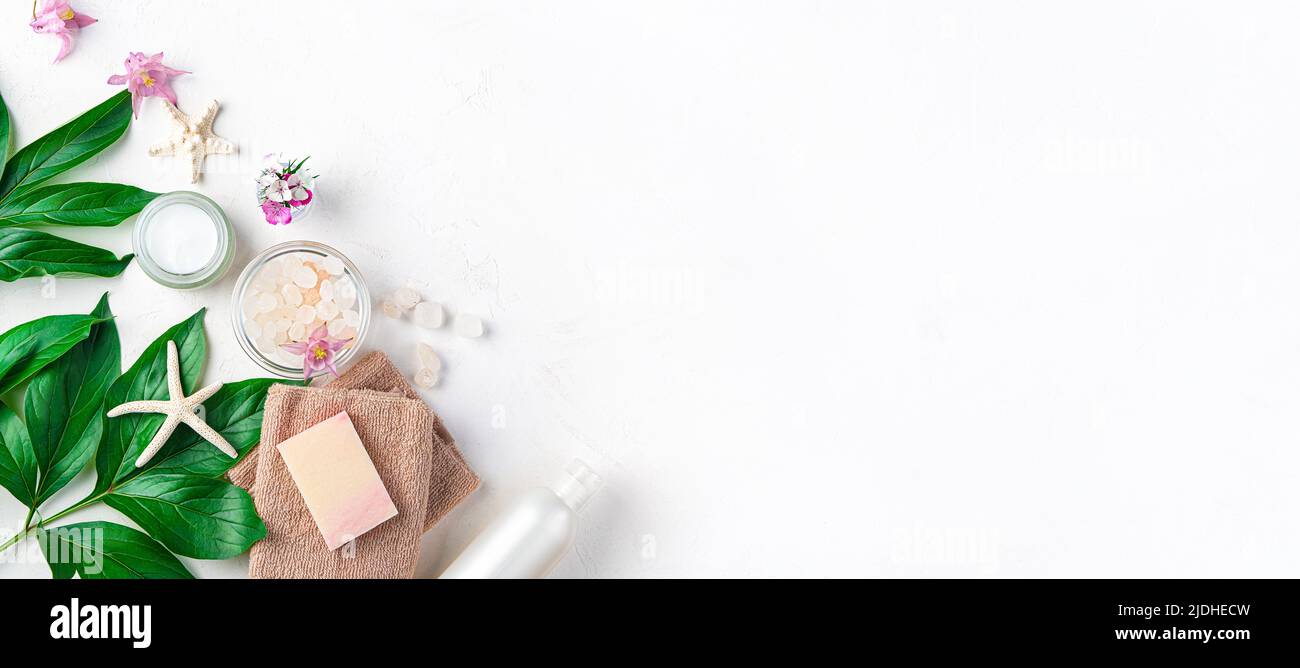 Spa-Komposition mit Handtuch, Seife, Creme und frischen Blumen. Stockfoto