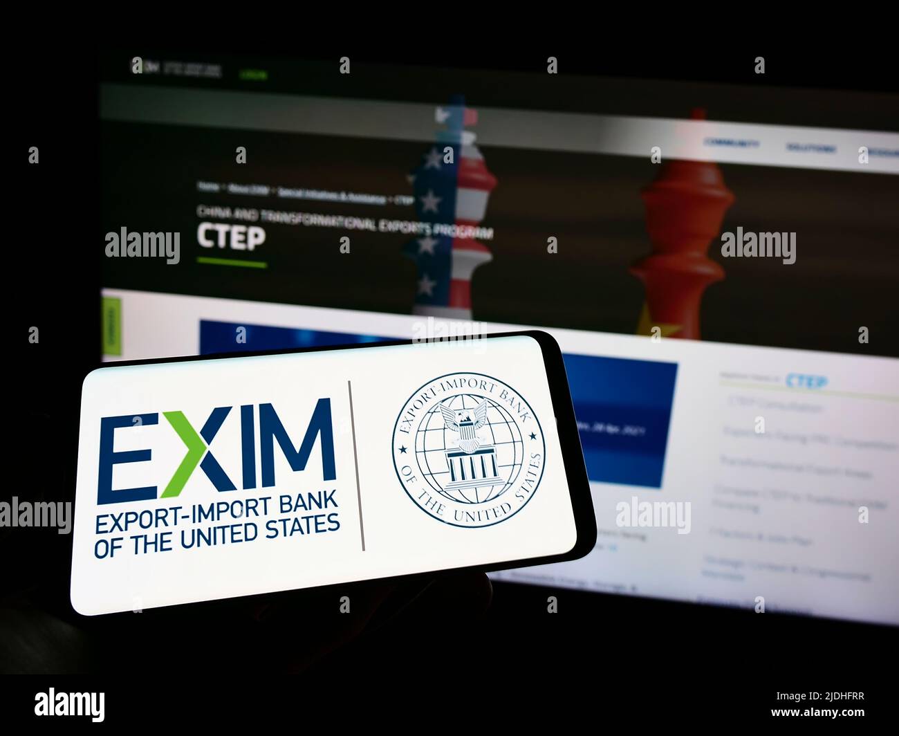 Person, die ein Mobiltelefon mit dem Logo der Export-Import Bank of the United States (Exim) auf dem Bildschirm vor der Webseite hält. Konzentrieren Sie sich auf die Telefonanzeige. Stockfoto