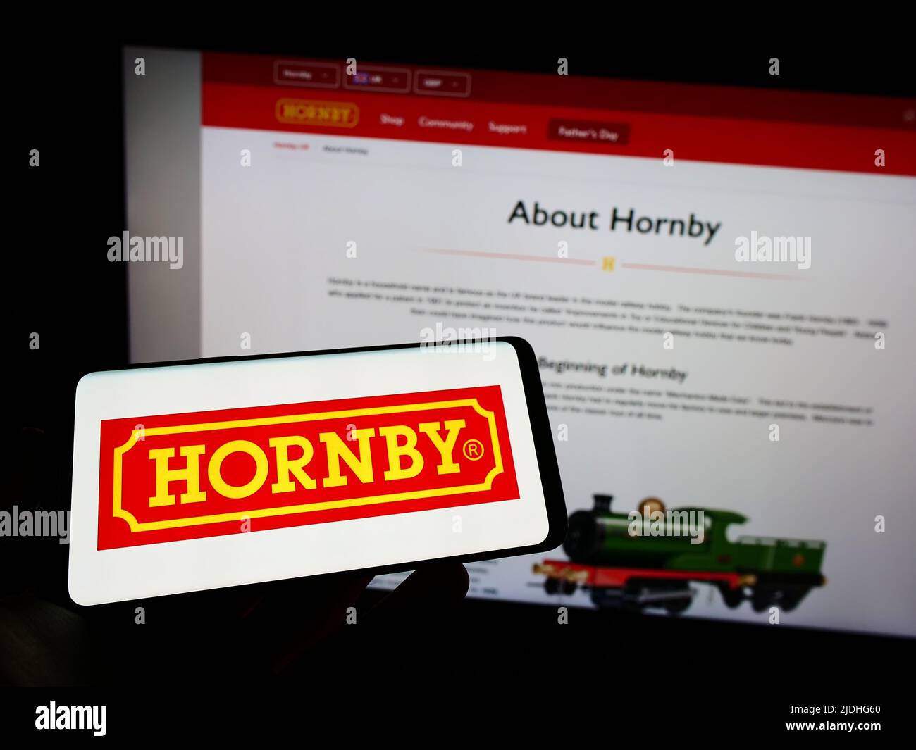 Person, die das Smartphone mit dem Logo der britischen Modelleisenbahngesellschaft Hornby plc auf dem Bildschirm vor der Website hält. Konzentrieren Sie sich auf die Telefonanzeige. Stockfoto