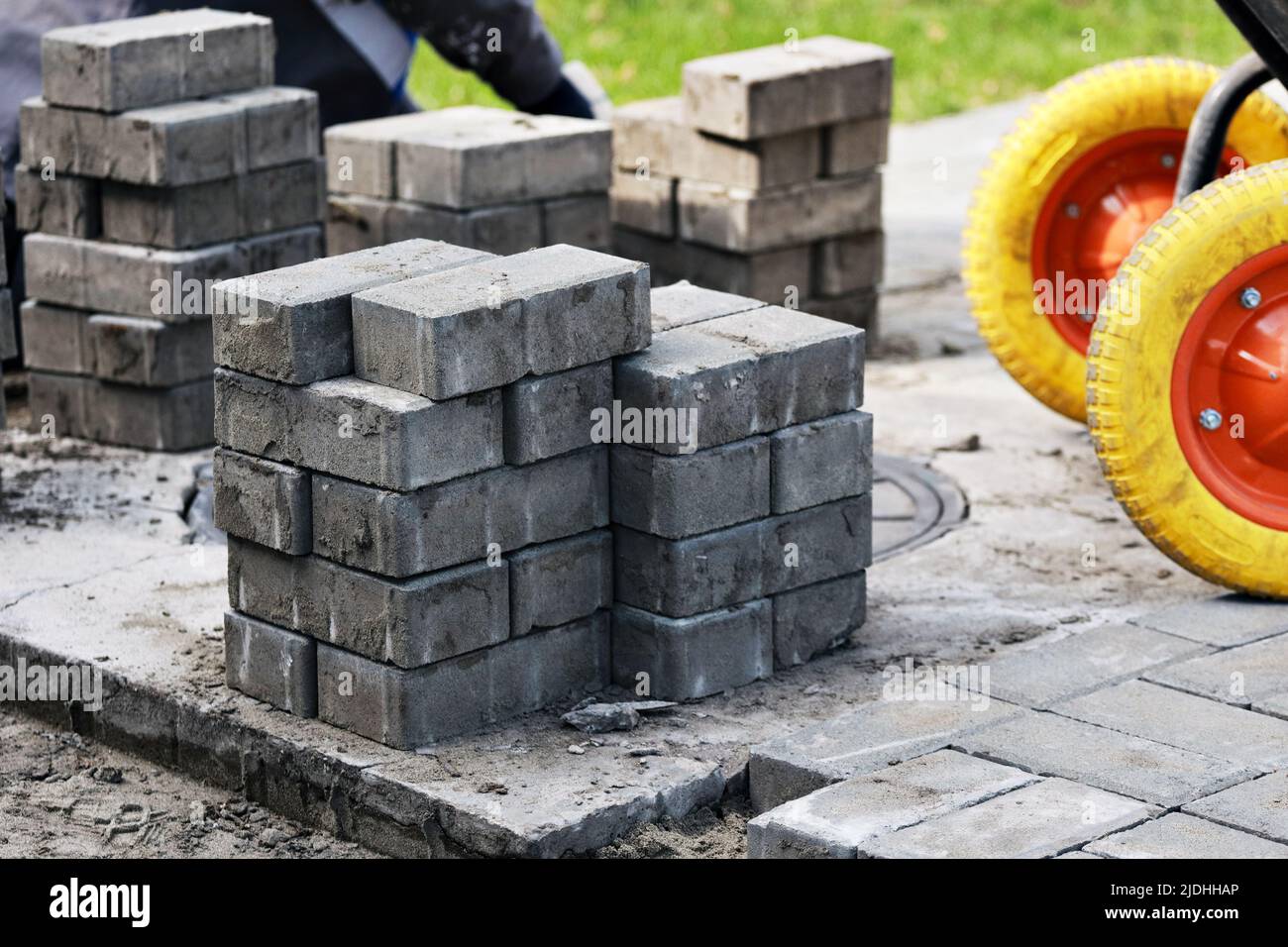 Blick auf neue Pflasterplatten und Betonblöcke am Sommertag auf der Baustelle. Steinblöcke stehen im Stapel. Reparatur von Platz und Gehwegen. Wiederherstellung der Fahrbahnoberfläche. Stockfoto