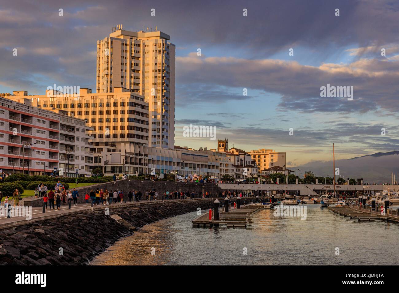 Dunkler Himmel über dem Hafen, während ein heller Sonnenuntergang die Marina-Hotels im Hafen von ponta delgada erleuchtet Stockfoto