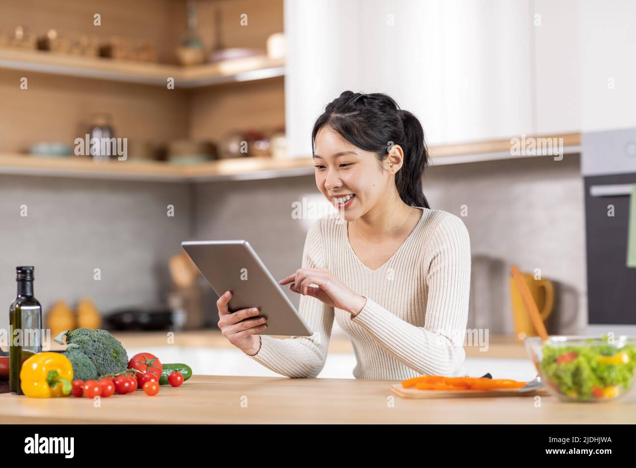 Fröhliche Frau Kochen Abendessen zu Hause, auf der Suche nach einem schönen Rezept Stockfoto