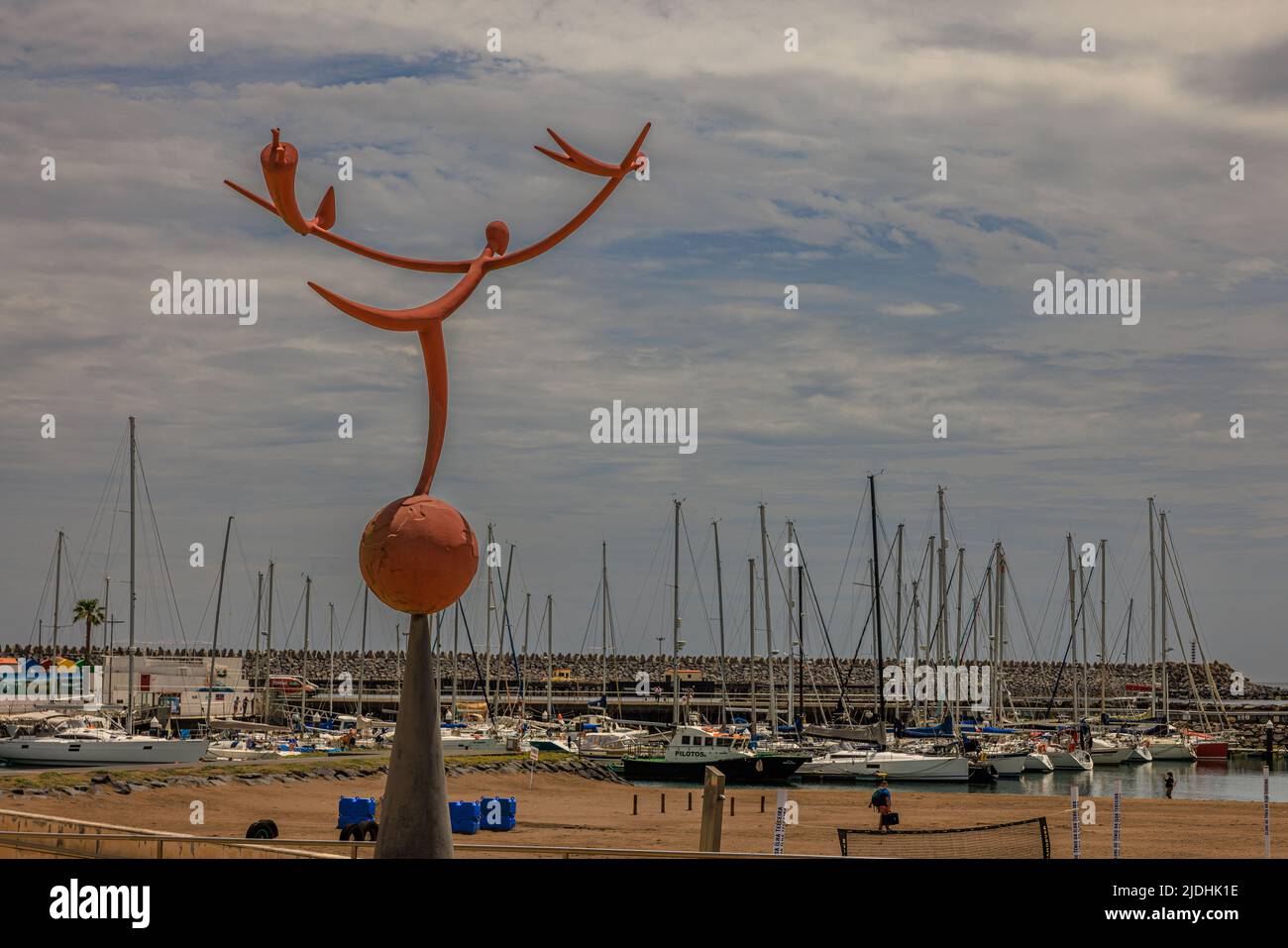 Eine moderne Statue einer Figur, die den Wind fängt und auf einem Globus steht und den geschäftigen Hafen von praia da vitoria beobachtet Stockfoto