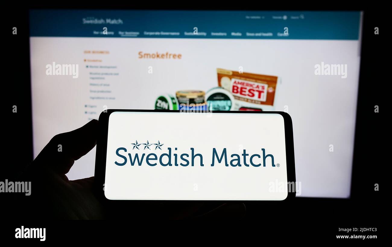 Person, die das Smartphone mit dem Logo des Tabakunternehmens Swedish Match ab auf dem Bildschirm vor der Website hält. Konzentrieren Sie sich auf die Telefonanzeige. Stockfoto