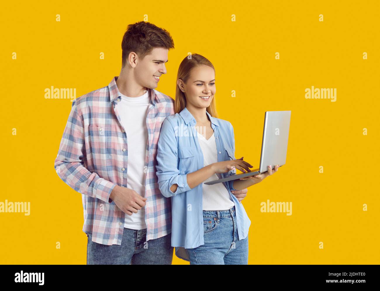 Das fröhliche junge Paar nutzt einen Laptop zum Online-Shopping, zum Buchen von Tickets oder zum Telefonat mit einem Videoanruf. Stockfoto