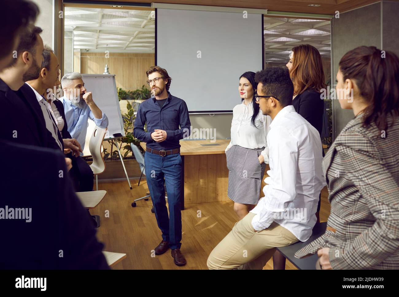 Verschiedene rassische, intelligente Mitarbeiter kommunizieren bei Teambesprechung im modernen Büro. Stockfoto