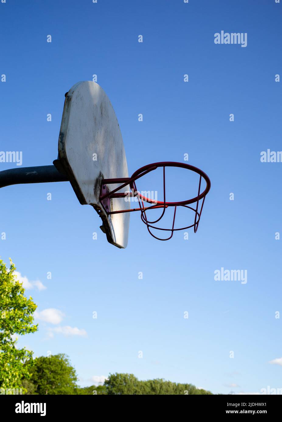 Basketballkorb und -Brett aus Metall gegen einen wolkenlosen, starken blauen Himmel mit Kopierfläche. Beleuchtet mit angestrahltem Sonnenlicht. Stockfoto