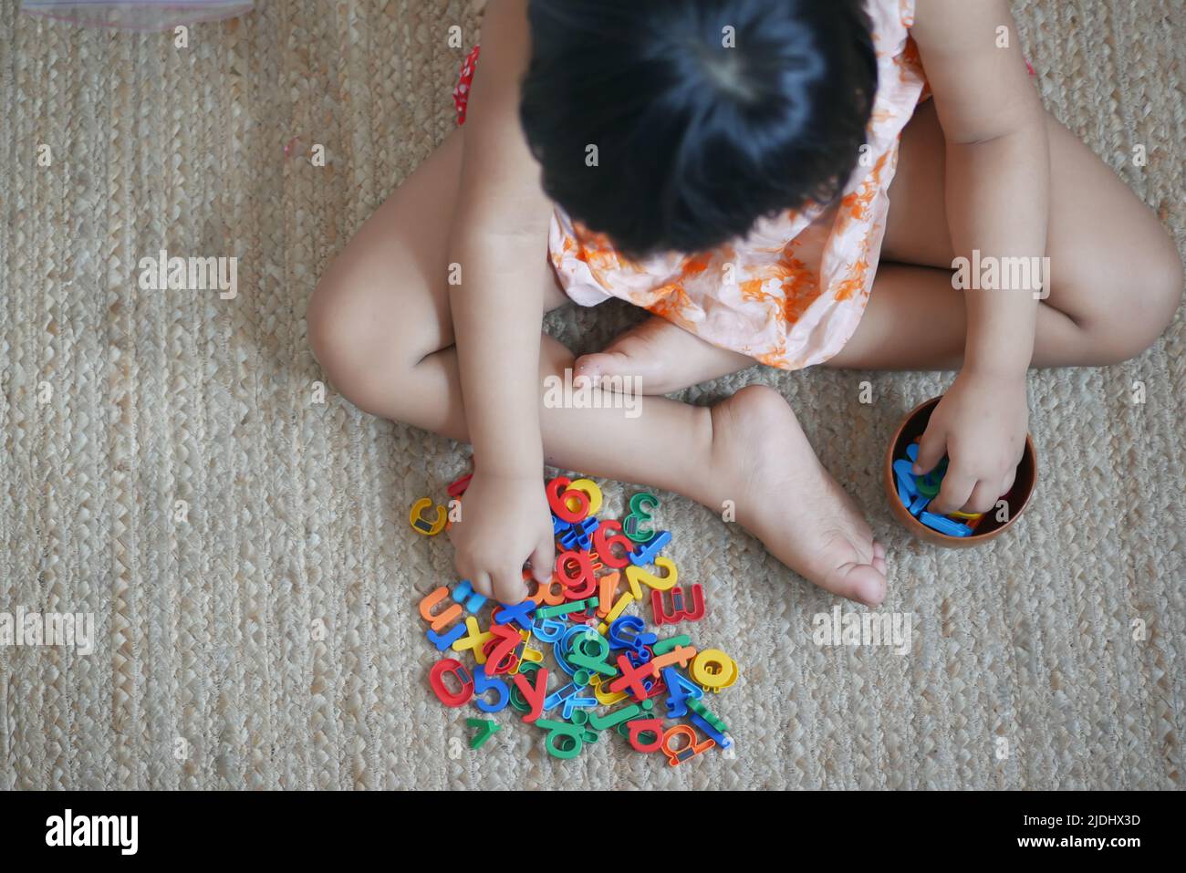 Kind Mädchen spielt mit bunten Plastikbuchstaben Stockfoto