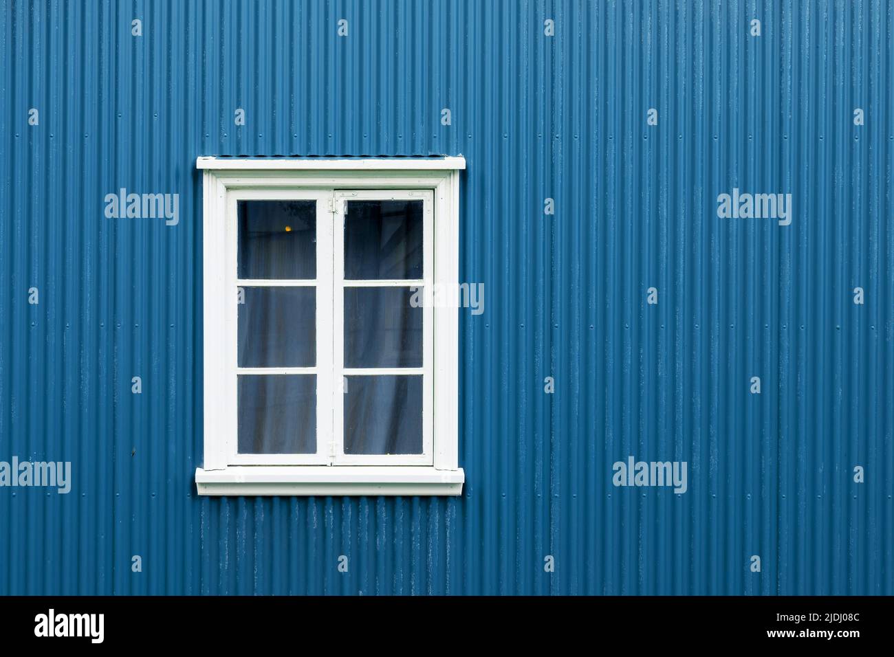 Fenster an einer blau gestrichenen Wand, buntes Haus, Architekturdetails in Reykjavik, Island Stockfoto