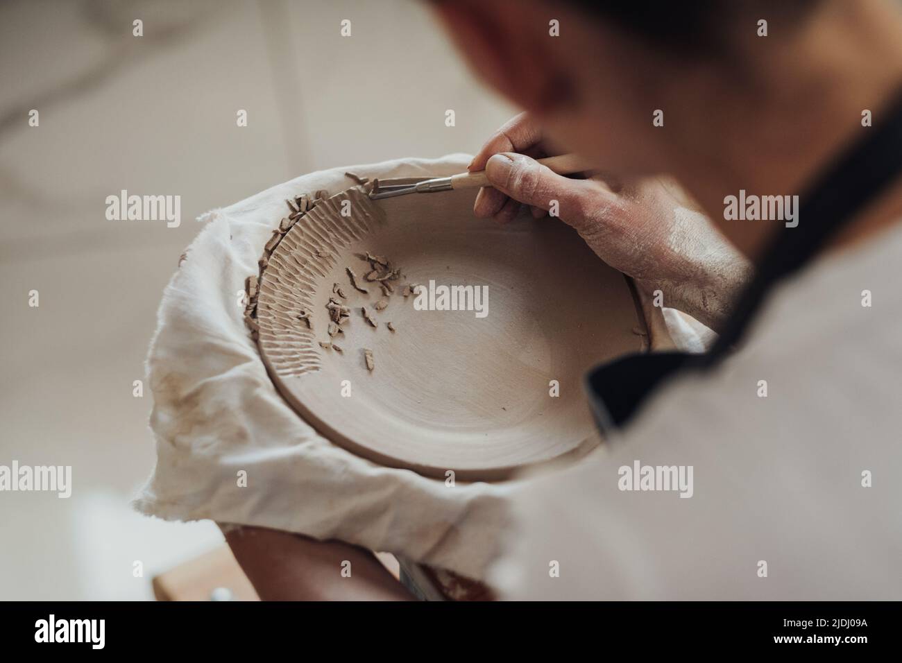 Nahaufnahme einer Töpferin bei der Arbeit, einer Frau, die Muster auf einer Tonplatte erstellt, Kunstarbeiten im Prozess Stockfoto