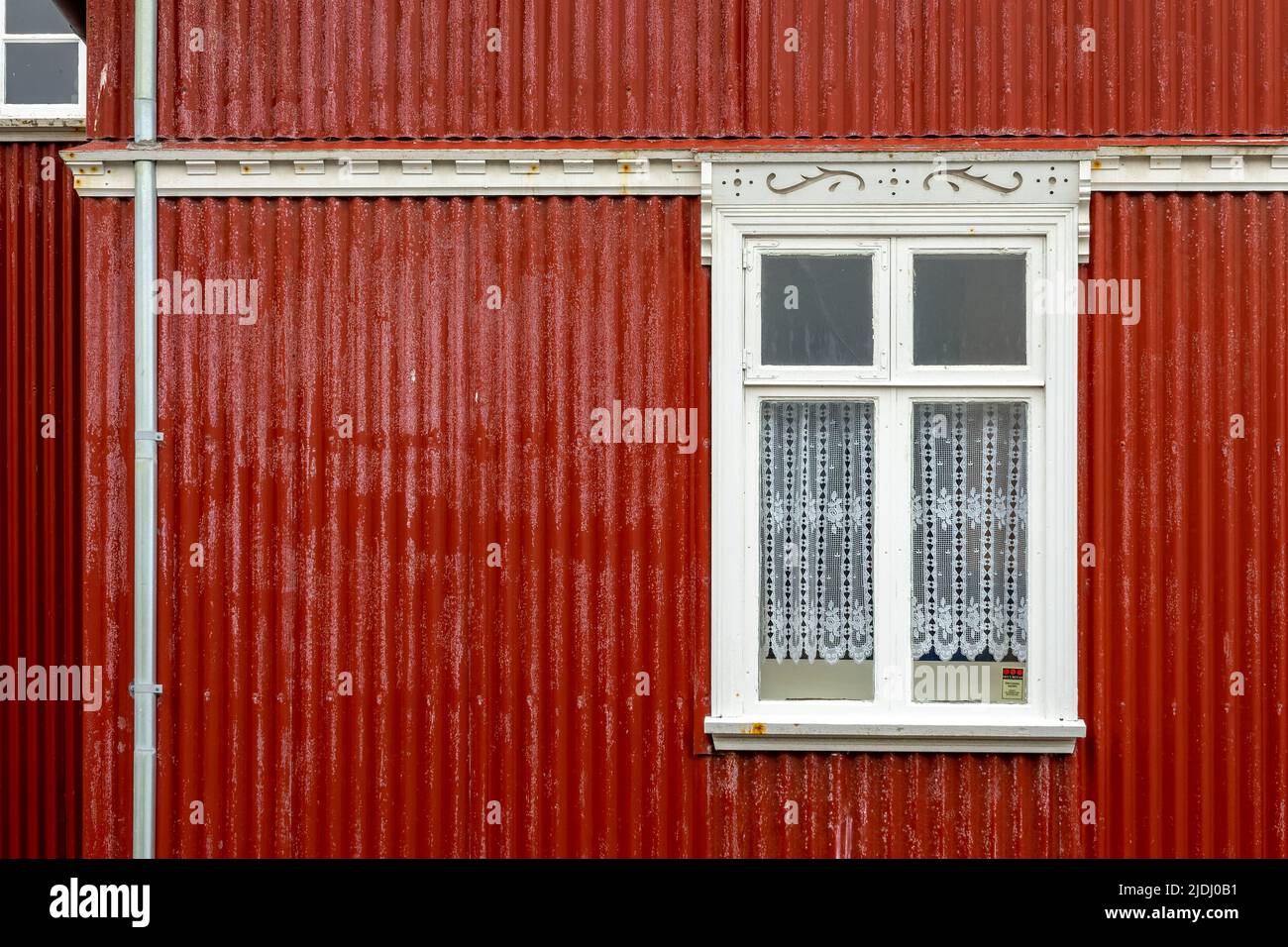 Fenster an einer rot gestrichenen Wand, buntes Haus, Architekturdetails in Reykjavik, Island Stockfoto