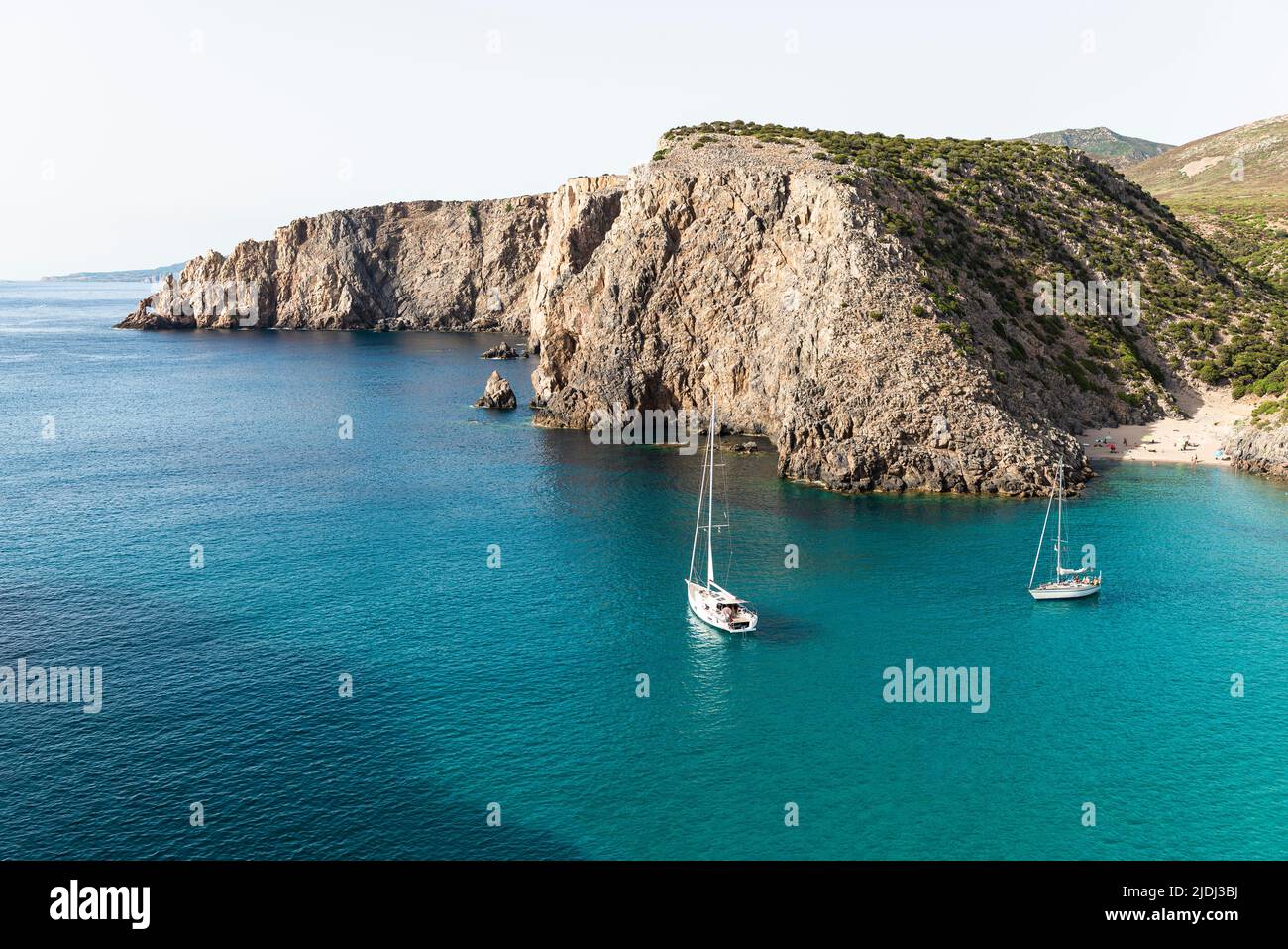 Segelboote in der fjordähnlichen Bucht von Cala Domestica mit dem Sandstrand von Cala Lunga, eingebettet zwischen felsigen Klippen im Südwesten Sardiniens Stockfoto