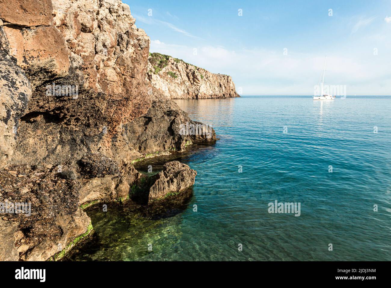 Segelboote in der fjordähnlichen Bucht von Cala Domestica mit dem Sandstrand von Cala Lunga, eingebettet zwischen felsigen Klippen im Südwesten Sardiniens Stockfoto