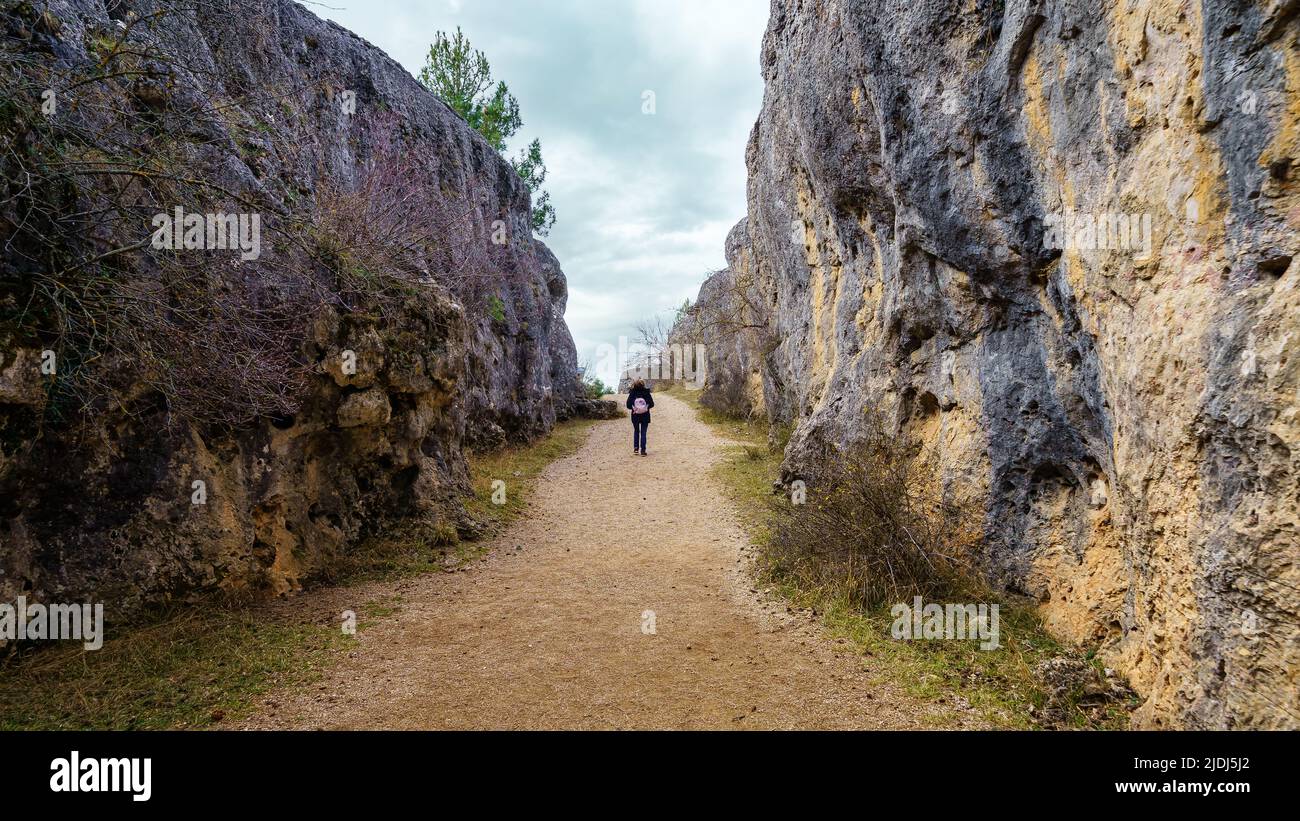 Frau, die zwischen hohen Kalksteinwänden in der Enchanted City von Cuenca, Spaon, läuft. Stockfoto