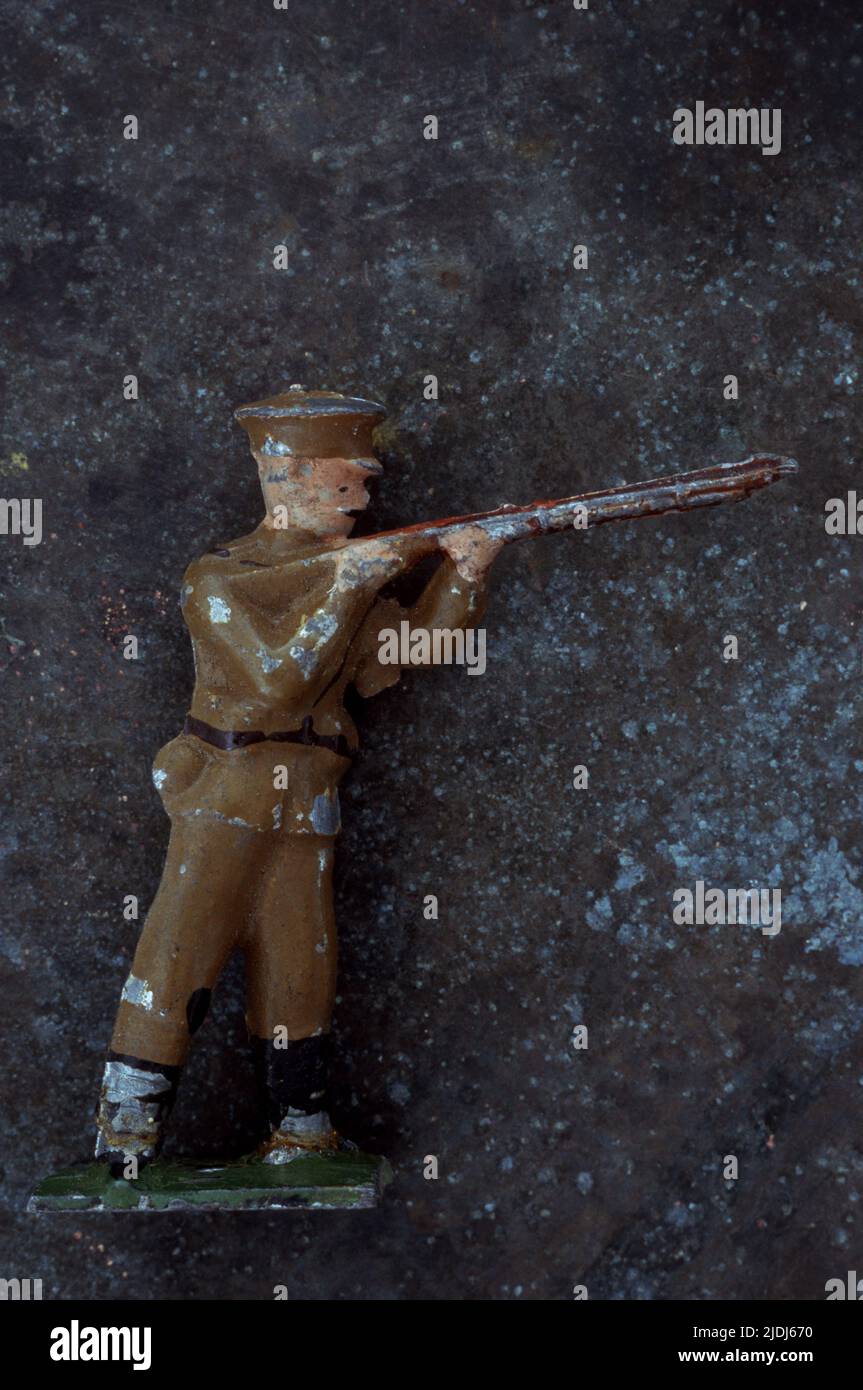 Abgenutztes Bleimodell des Armeeoffiziers aus dem 1. Weltkrieg, das auf einen gesprenkelten Metallhintergrund zielt und das Gewehr abfeuert Stockfoto