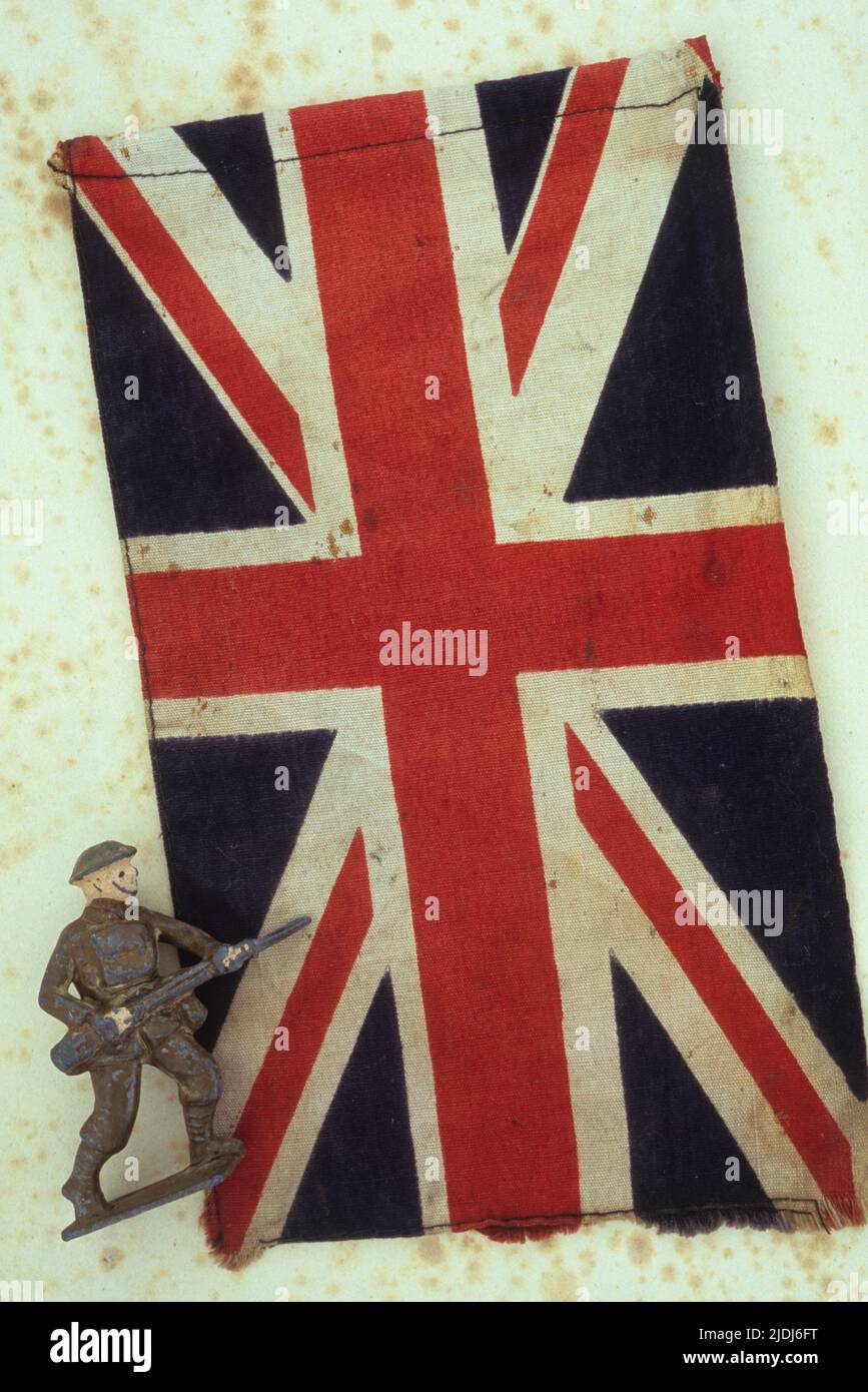 Markierte und befleckte Union Jack-Flagge auf antikem Papier mit abgenutztem Bleimodell des 2. Weltkrieges Armee-Fußsoldaten mit Gewehr Stockfoto
