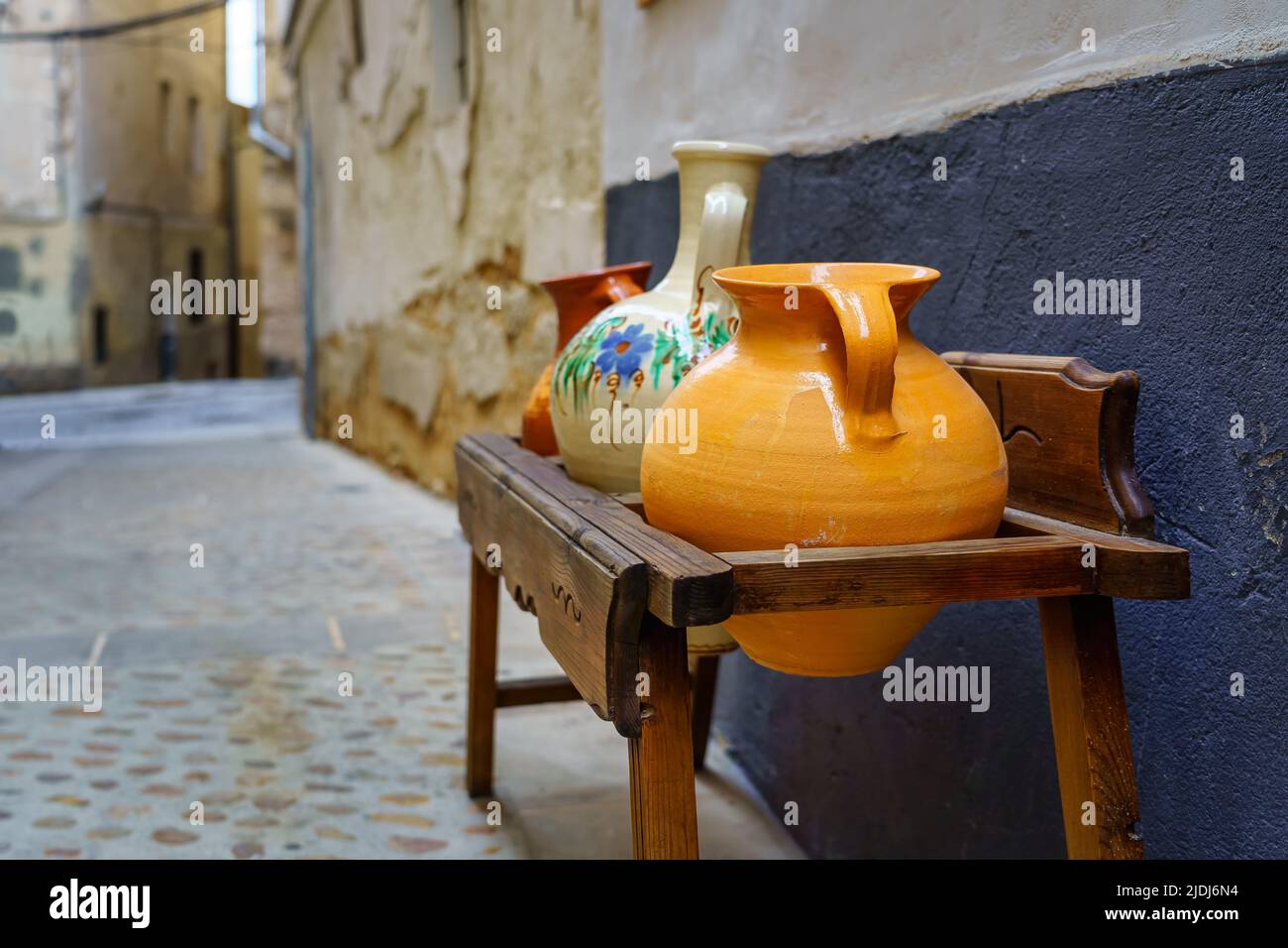 Antike Holzmöbel mit bunten Tontöpfen in einer mittelalterlichen Stadt. Spanien. Stockfoto