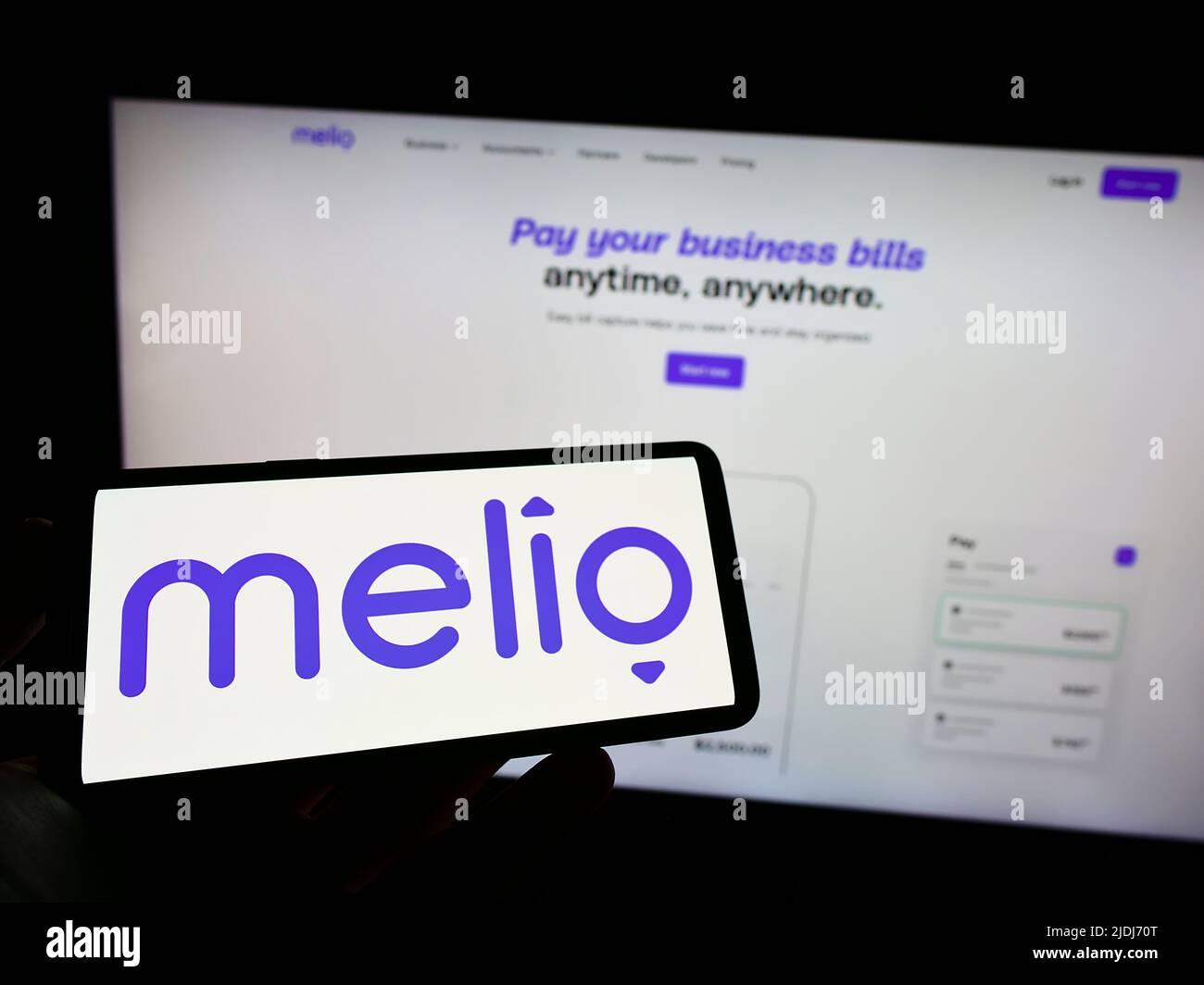 Person mit Mobiltelefon und Logo des amerikanischen Finanzunternehmens Melio Payments Inc. Auf dem Bildschirm vor der Webseite. Konzentrieren Sie sich auf die Telefonanzeige. Stockfoto