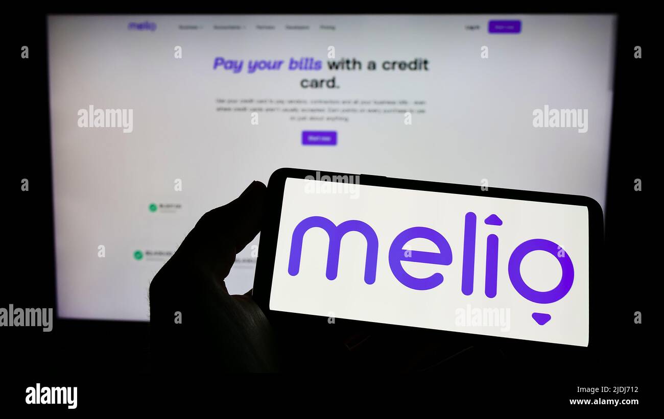 Person, die Mobiltelefon mit dem Logo des US-Finanzunternehmens Melio Payments Inc. Auf dem Bildschirm vor der Business-Webseite hält. Konzentrieren Sie sich auf die Telefonanzeige. Stockfoto
