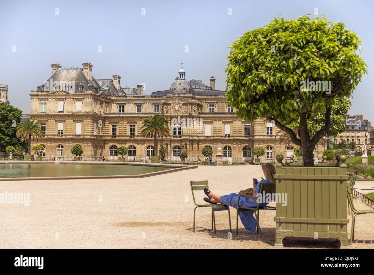 PARIS, FRANKREICH - 19. JUNI 2022: Der Palast von Luxemburg im Jardin du Luxembourg an einem heißen Sommertag. Frau relxing im Schatten eines Baumes. Stockfoto