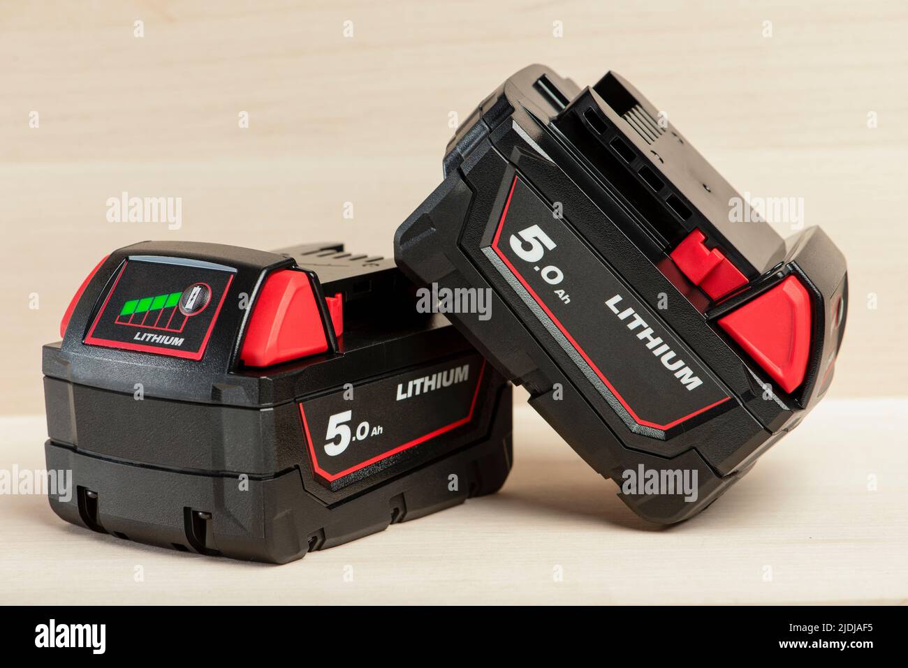 Lithium-Akku für Akku-Bohrmaschine. Schrauberbatterie. Vier Batterien mit Ladeanzeige liegen auf einem Holzhintergrund Stockfoto