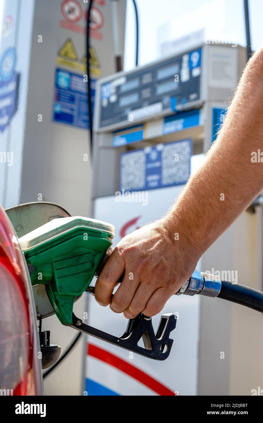 Mann pumpt Benzin in einem Auto an einer Self-Service-Tankstelle. Hand hält eine Pistole oder eine Düsenpumpe, die den Autotank betankt. Stockfoto