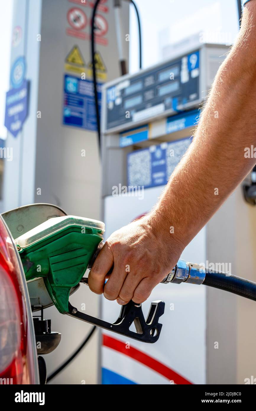 Mann pumpt Benzin in einem Auto an einer Self-Service-Tankstelle. Hand hält eine Pistole oder eine Düsenpumpe, die den Autotank betankt. Stockfoto