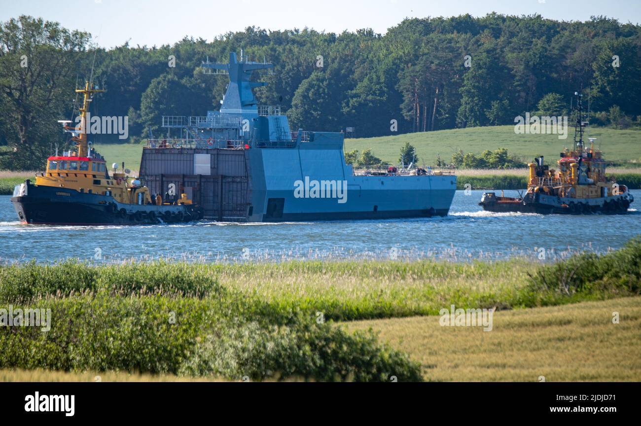 21. Juni 2022, Mecklenburg-Vorpommern, Wolgast: Ein Rumpfsegment (Achterschiff) einer K130 Korvette wird von Schleppern vom NVL-Standort der Peene-Werft zum NVL-Standort Blohm Voss in Hamburg gebracht, um dort die andernorts gebauten Vorschiffe zu verbinden. Die ersten fünf Boote der neuen K130-Klasse sind bereits seit 2008 in Betrieb, fünf weitere folgen. Zwei der vier noch ausstehenden Kriegsschiffe werden derzeit ebenfalls ausgerüstet. Boot 9 befindet sich nach Angaben der Marineschiffe Lürssen (NVL) in der Produktionsphase, und Boot 10 hatte seinen Kiel Anfang dieses Jahres gelegt. Nach Angaben des Unternehmens, bei der Peene Stockfoto