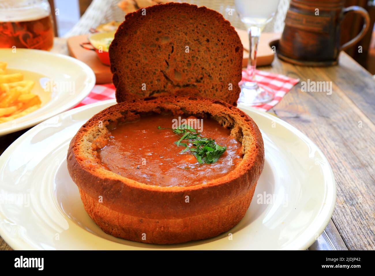 Originalgericht - Gulaschsuppe im Brottopf, Teller im Restaurant, Café. Köstliche herzhafte Fleischgericht der tschechischen, bulgarischen, rumänischen Küche, europäischen recip Stockfoto