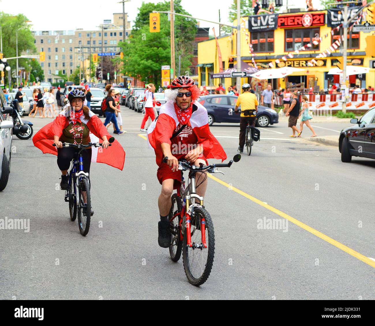 Ottawa, Kanada - 1. Juli 2013: In Flaggen gehüllte Feiernden des Canada Day fahren am Canada Day auf dem Byward Market mit dem Fahrrad. Stockfoto