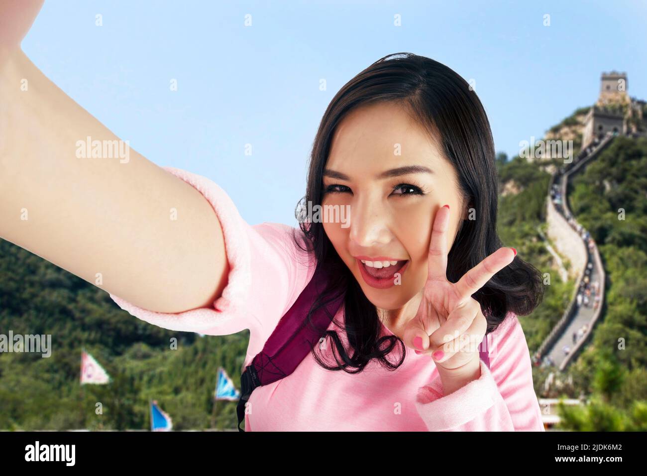 Foto einer Frau mit dem Gesicht einer Touristen und ihrer Hand, auf dem sie V-Sing zeigte, während sie Selfie mit der Chinesischen Mauer auf dem Boden machte. Stockfoto