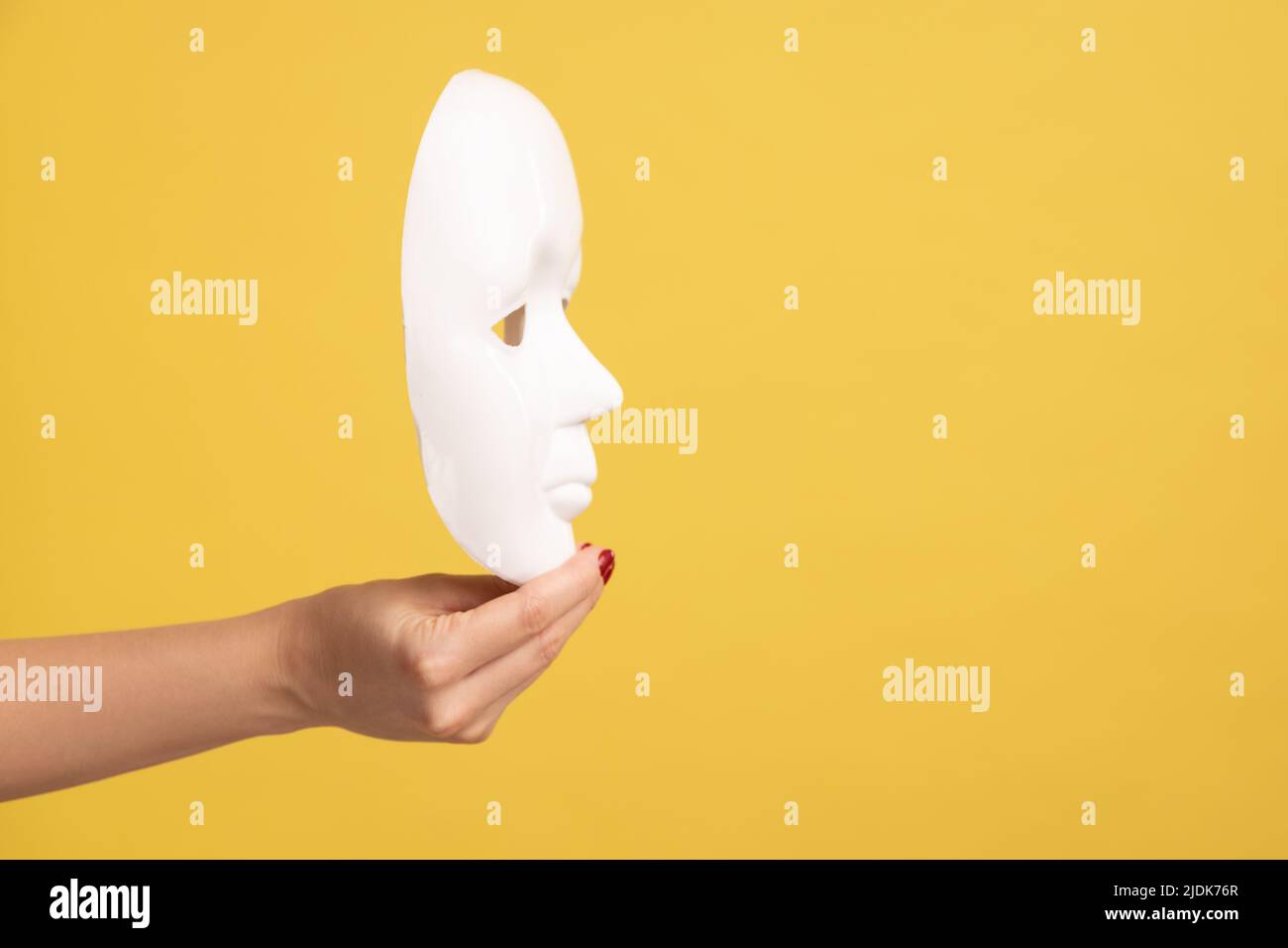 Profil Seitenansicht Nahaufnahme der Frau Hand hält weiße Gesichtsmaske Modell, versteckt Persönlichkeit. Innenaufnahme des Studios isoliert auf gelbem Hintergrund. Stockfoto Profil Seitenansicht Nahaufnahme der Frau Hand hält weiße Gesichtsmaske Modell, versteckt Persönlichkeit. Innenaufnahme des Studios isoliert auf gelbem Hintergrund. Stockfoto