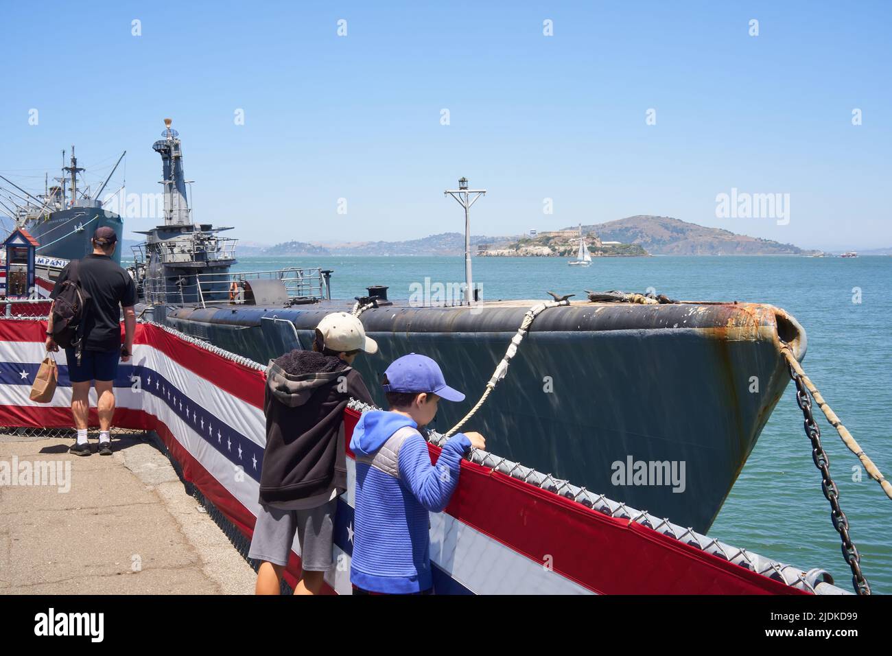 Zwei kleine Jungen bewundern das ehemalige U-Boot USS Pampanito in San Francisco, Kalifornien, mit Alcatraz Island im Hintergrund. Stockfoto