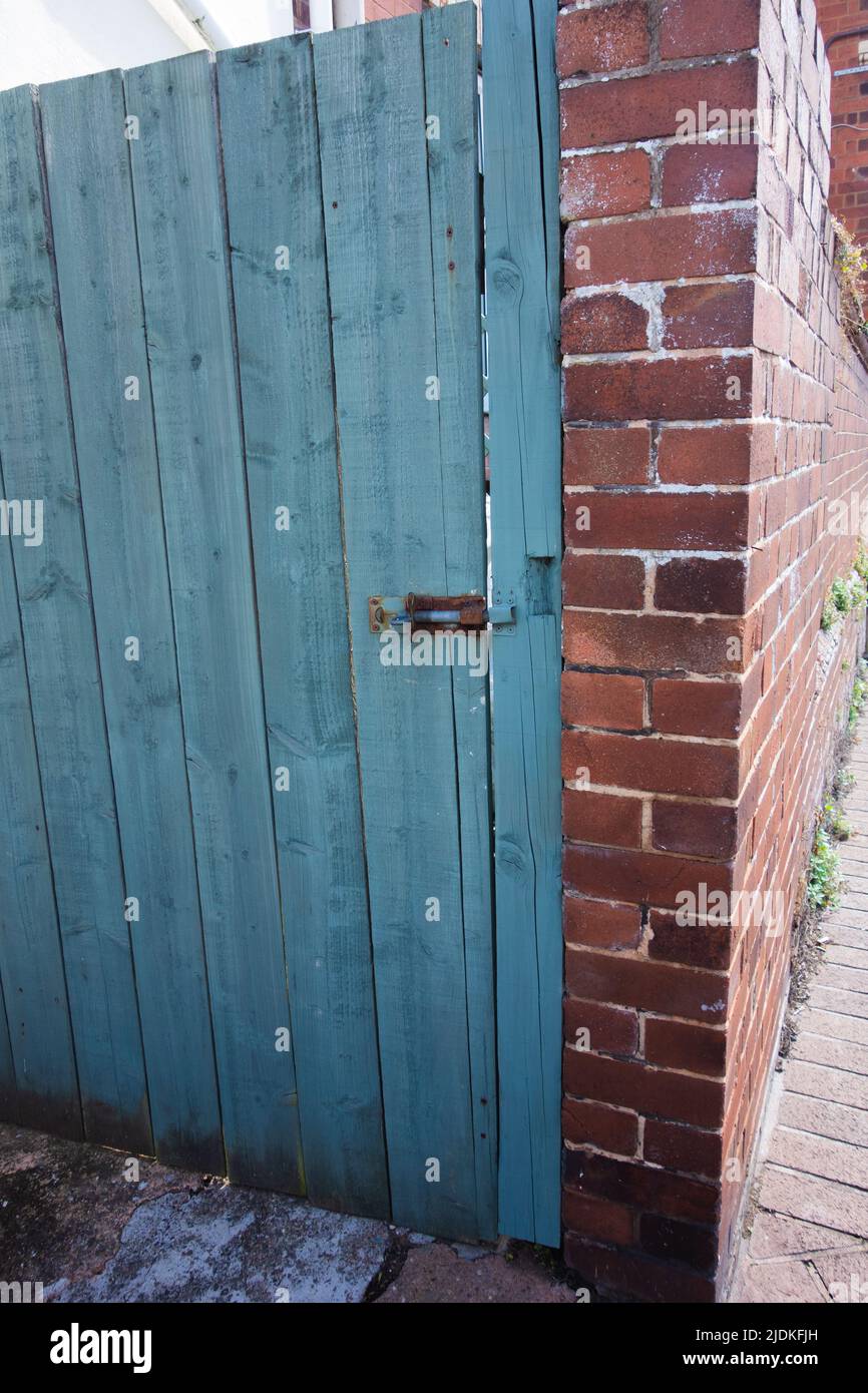 Alte Holztür mit verrosteten Bolzen in einer neuen Ziegelwand Stockfoto