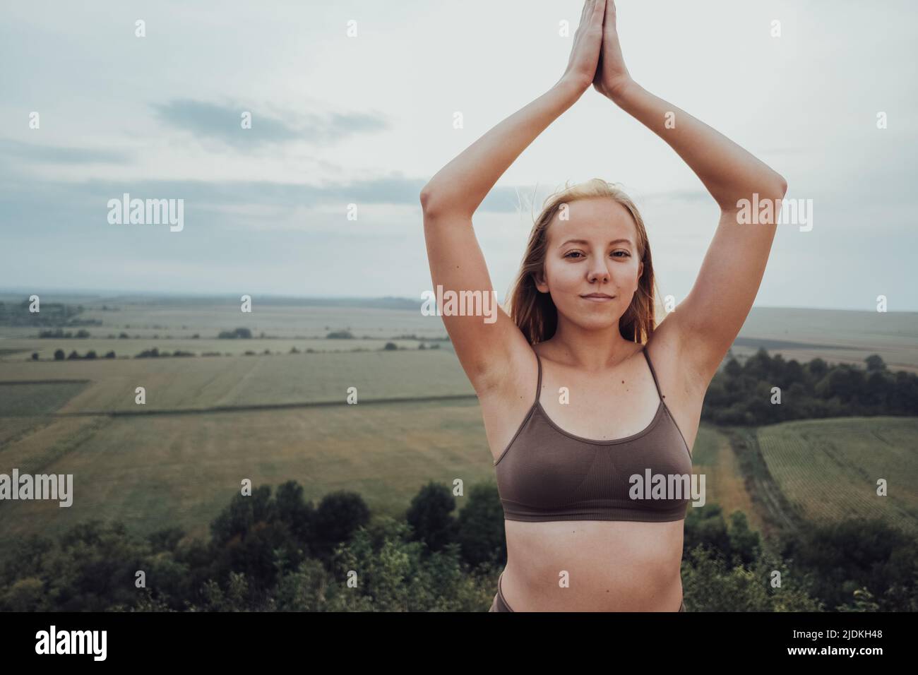 Nahaufnahme Junge kaukasische Frau praktiziert Yoga im Freien mit Panoramalandschaft bei Sonnenuntergang, Sportliches Mädchen macht Meditationsübungen auf einem Hügel Stockfoto