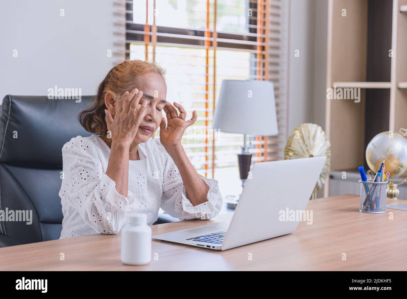 Business Senior Asian Elder Frau Kopfschmerzen Migräne krank von der Arbeit Blick auf den Computer-Bildschirm lange Zeit. Stockfoto