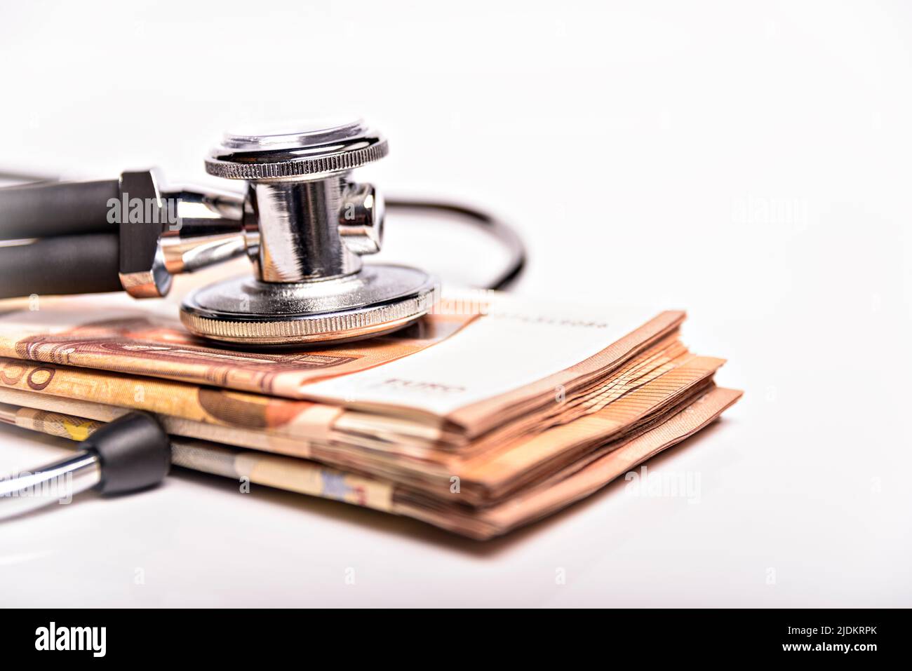 Gesundheitskosten konzeptionelles Bild: Stethoskop und Geldhaufen auf einer medizinischen Karte, Symbol der Gesundheitskosten oder Krankenversicherung, isoliert auf Stockfoto