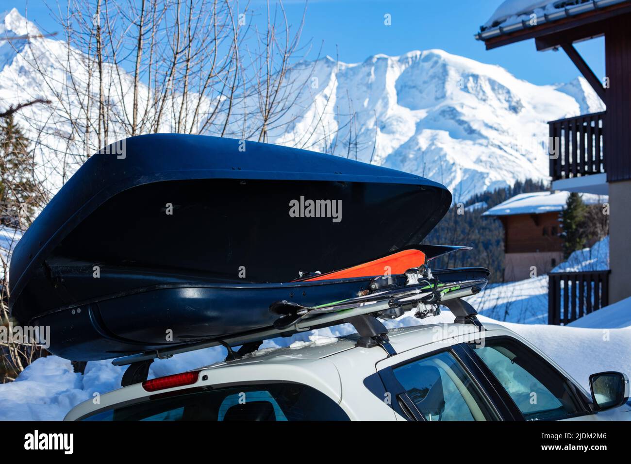 Autokasten auf dem Dach mit Ski im Inneren über Berggipfel Stockfoto