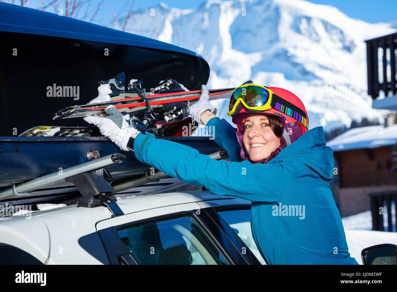 Frau legte Ski in die Autokiste auf dem Dach und drehte sich zurück und lächelte Stockfoto