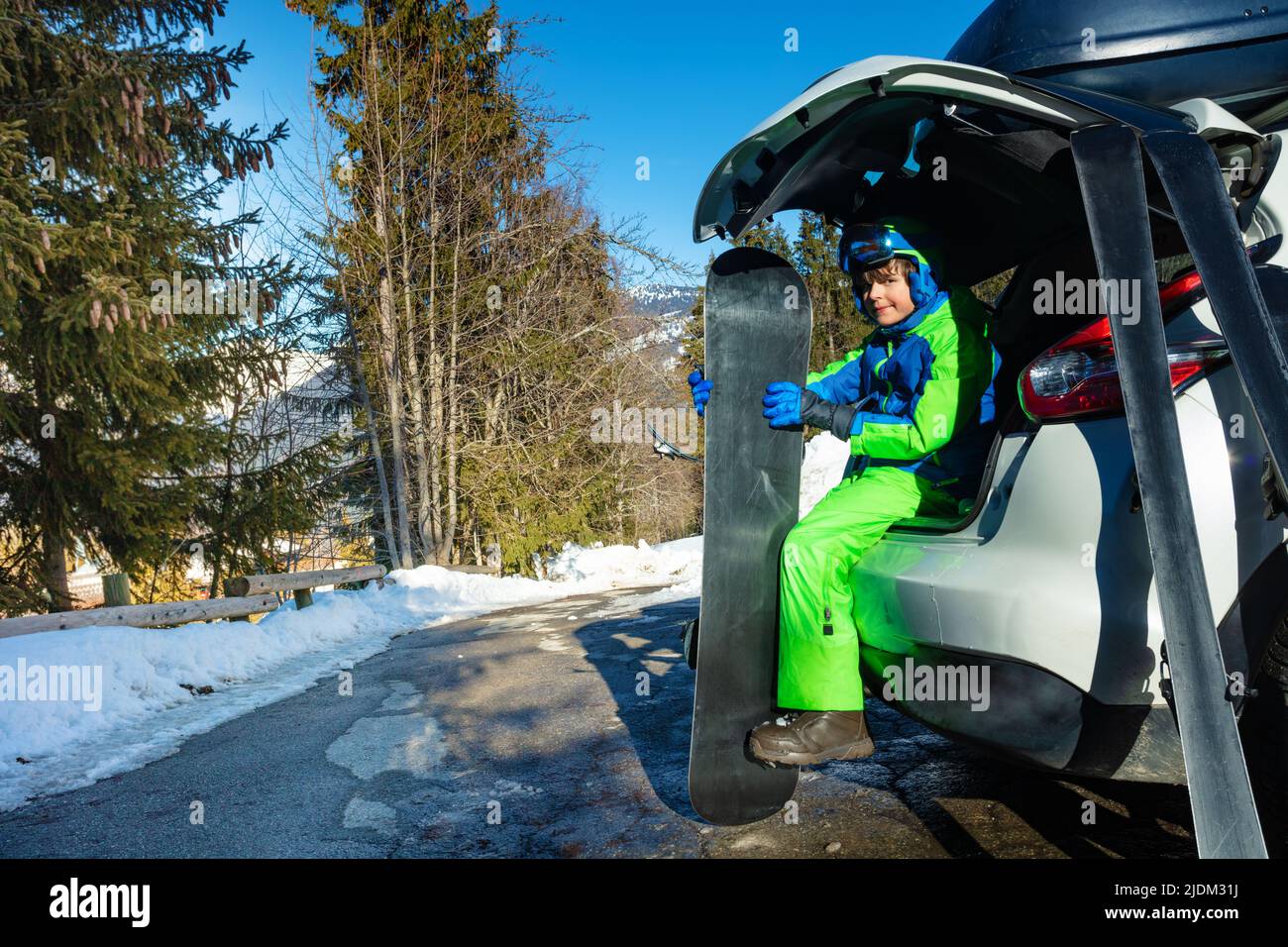 Boy mit Snowboard und Sporthelm, Maske sitzen im Kofferraum Stockfoto