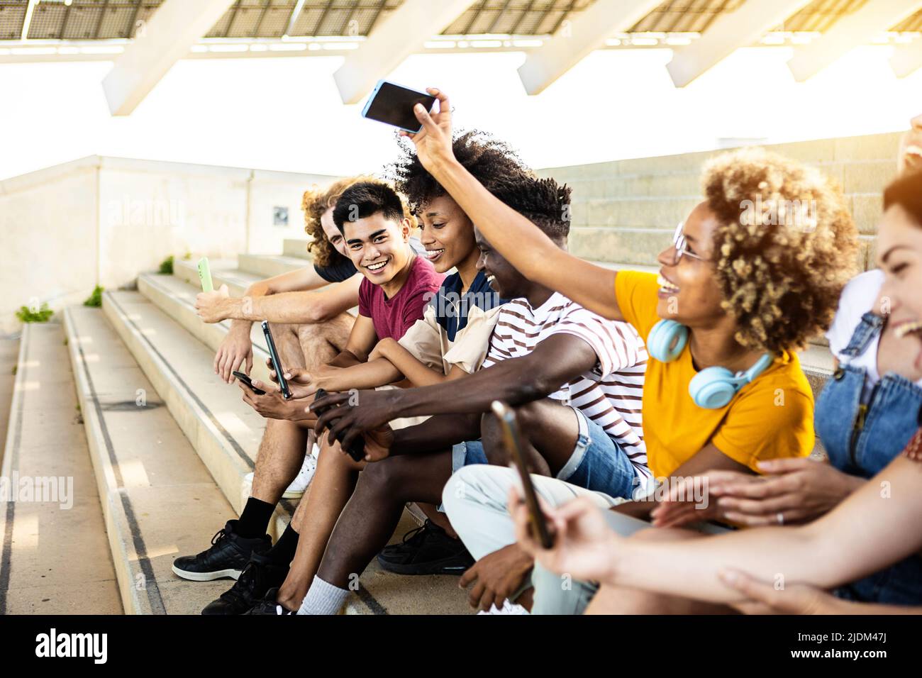 Multirassische Gruppe von Teenagern, die im Freien ein Mobiltelefon benutzen Stockfoto