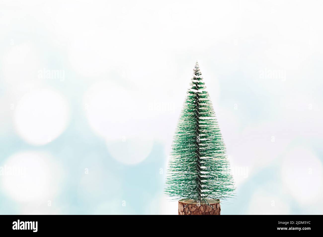 Grüner Weihnachtsbaum auf einem blauen abstrakten Winterhintergrund mit schimmernden weißen Sonnenflecken. Bokeh. Neujahrs- und Weihnachtskonzept. Platz für Text kopieren. Stockfoto