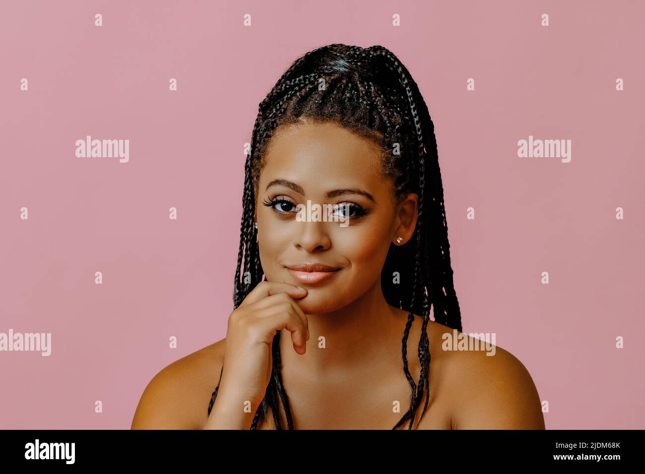 Porträt von jungen Erwachsenen nachdenklich Schönheit schwarze Frau mit Hand auf Kinn Zopf Haare auf rosa Hintergrund Studio-Aufnahme Stockfoto