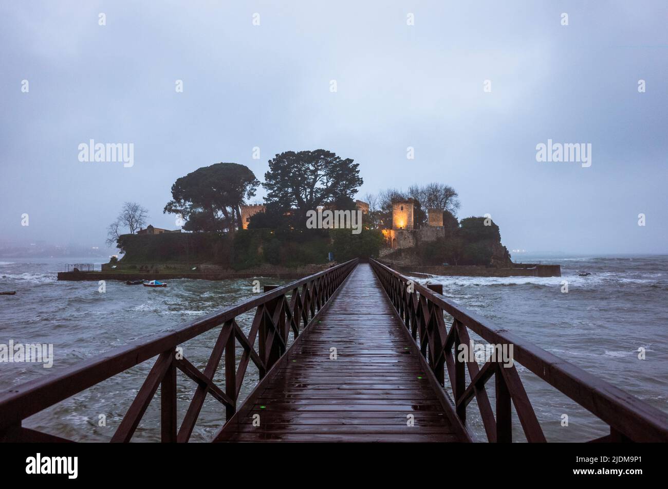 Oleiros, PROVINZ Coruña, Galicien, Spanien - 11. Februar 2020 : Fußgängerbrücke zur Insel Santa Cristina mit beleuchteten Santa Cruz Schloss auf Sa Stockfoto