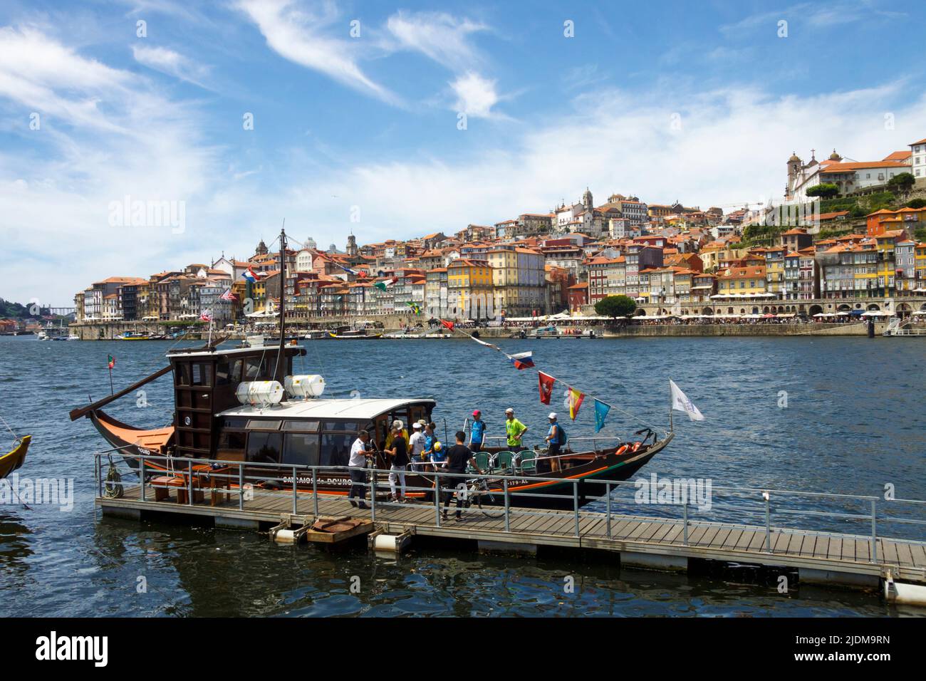 Porto, Portugal : Touristen steigen an Bord eines Bootes gegenüber den farbenfrohen Gebäuden am Douro-Ufer. Stockfoto