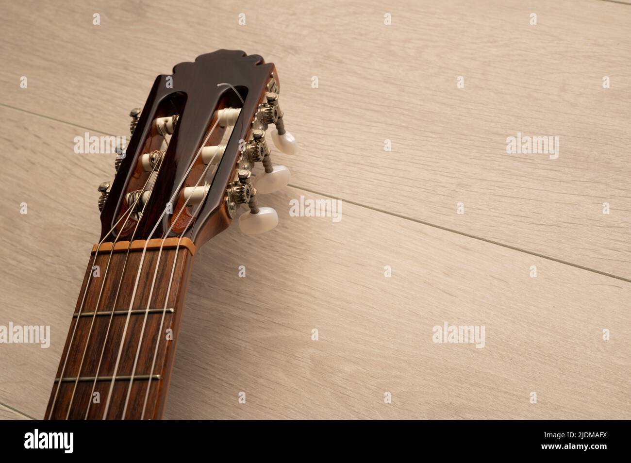 Klassische Gitarre Griffbrett und Maschine Kopf aus der Nähe auf einem hellen Holz Hintergrund mit Kopierraum Stockfoto