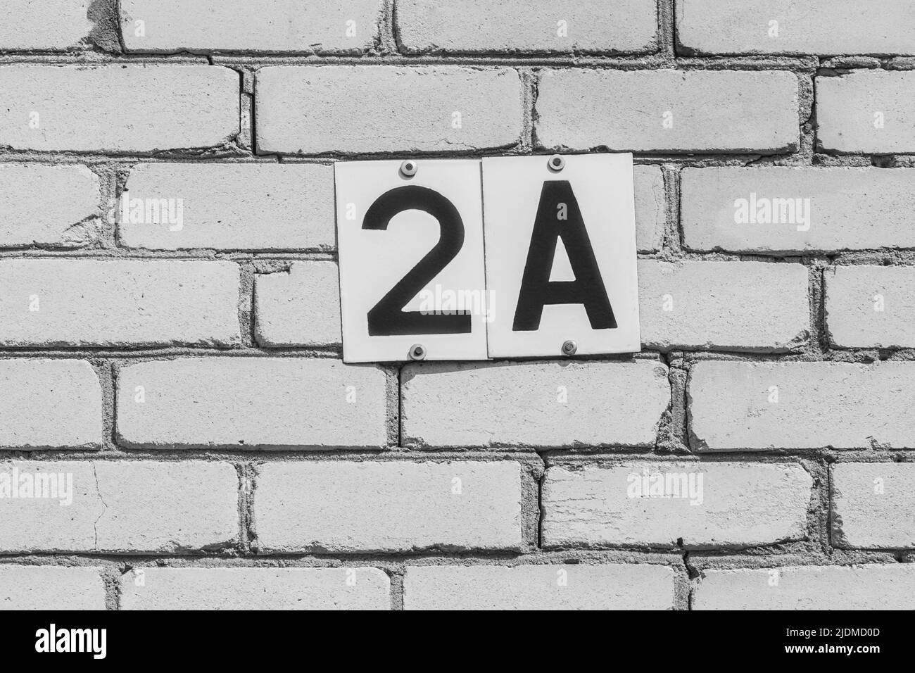 Nummer 2 und Ein Zeichen Symbol Ziffer Adresse Nummerierung auf der weißen Backsteinmauer des Hauses außen, Nahaufnahme. Stockfoto