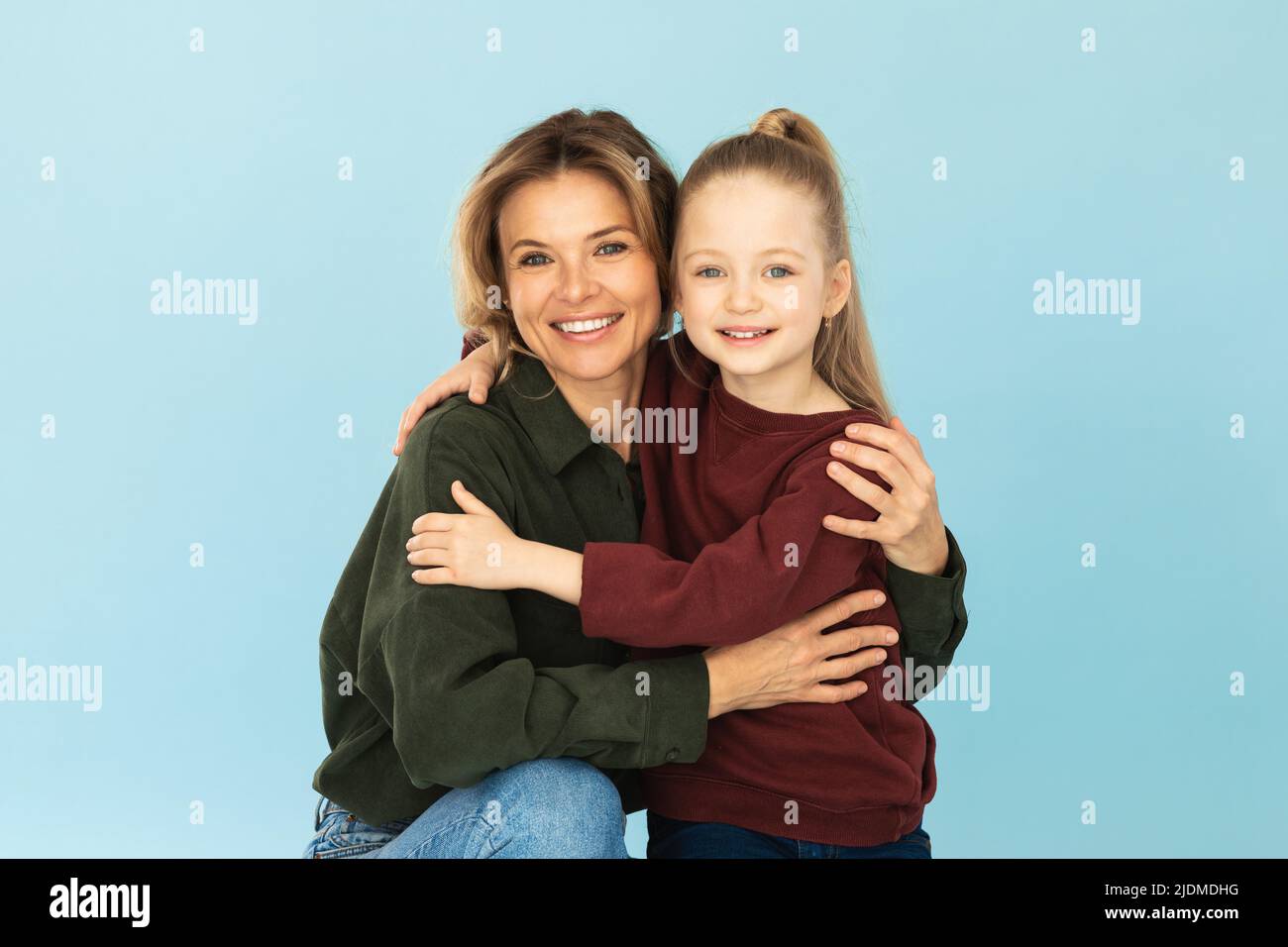 Fröhliche Mama Umarmt Liebenswert Kleine Tochter Posiert Über Blauen Hintergrund Stockfoto