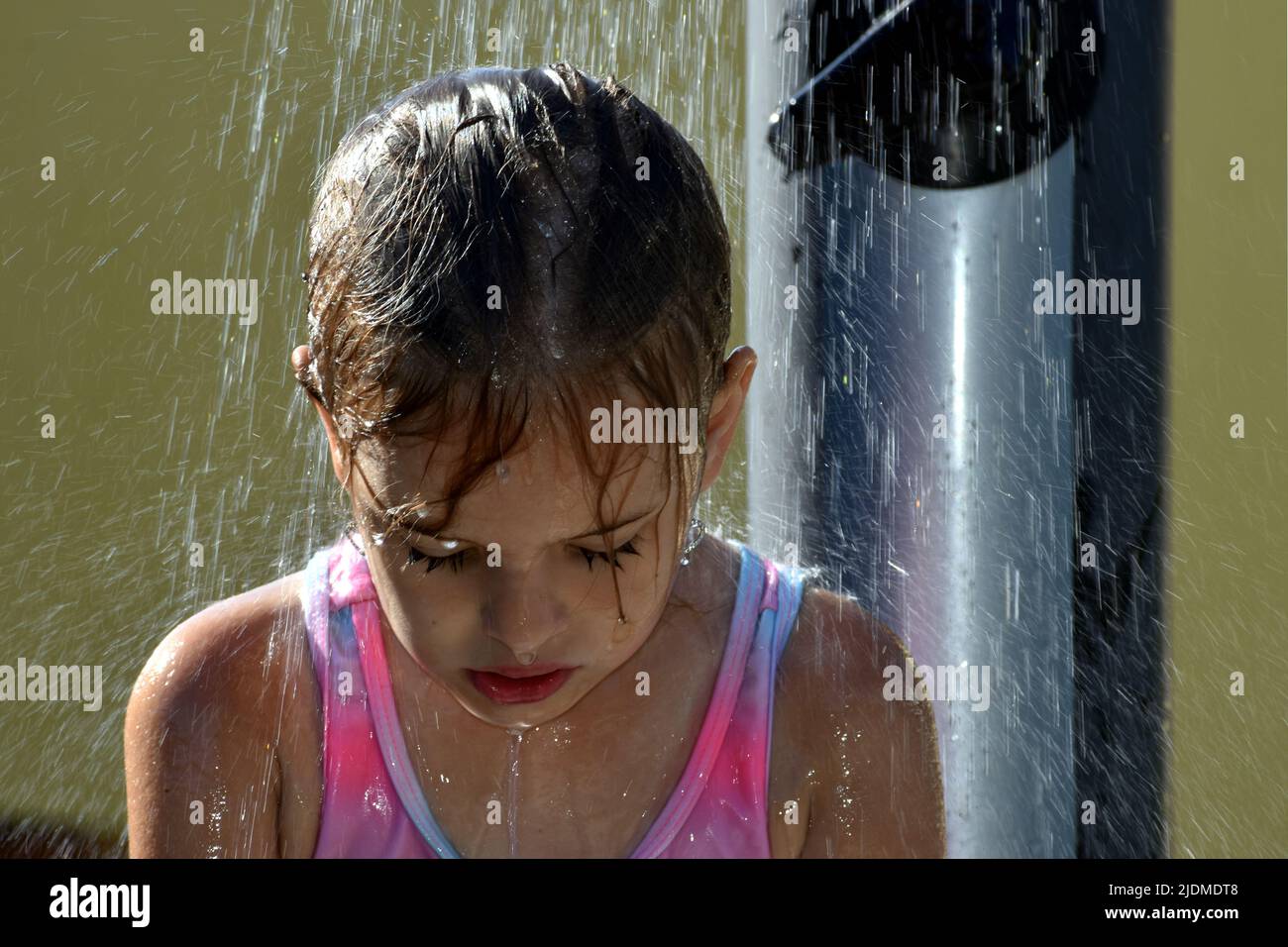 Das Kind kühlt sich während des heißen Wetters im Sommer unter einer Außendusche ab Stockfoto