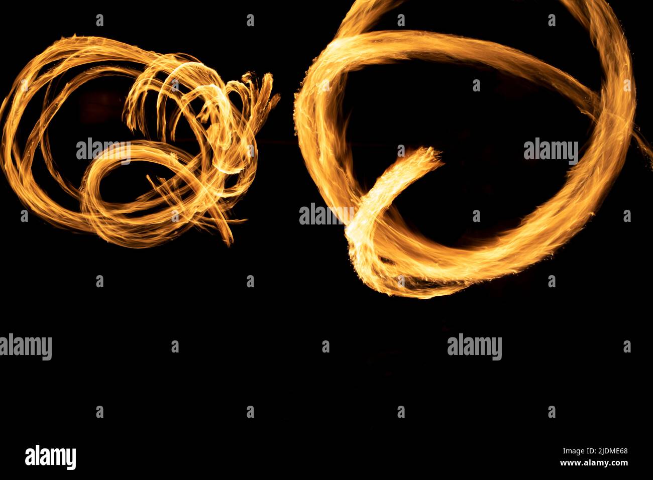 Kreise von Flammen im Dunkeln. Feuershow bei langer Verschlusszeit der Kamera. Flammen. Feuer auf schwarzem Hintergrund. Stockfoto